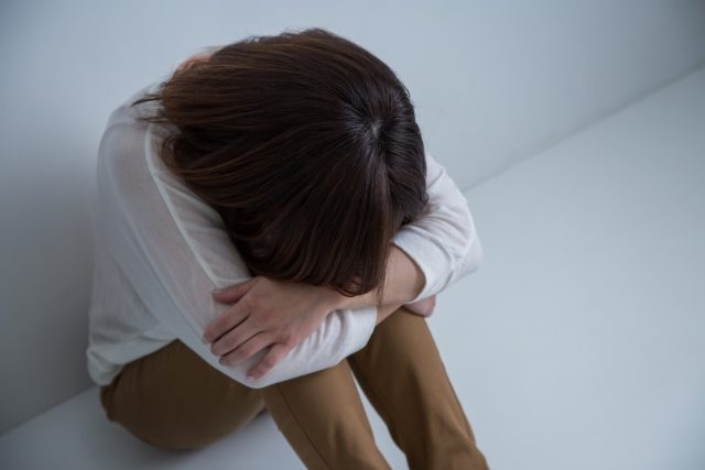 膝を抱える女性の写真